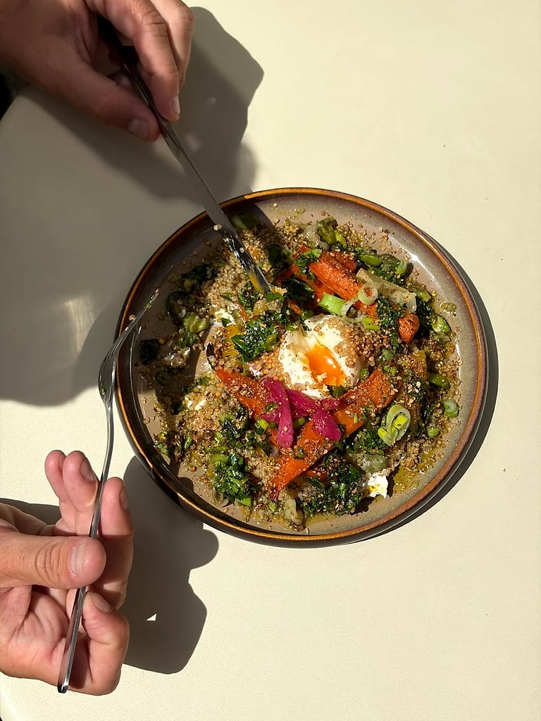 Un bol de légumes rôtis et d'herbes, vu de dessus, dans la lumière du midi.