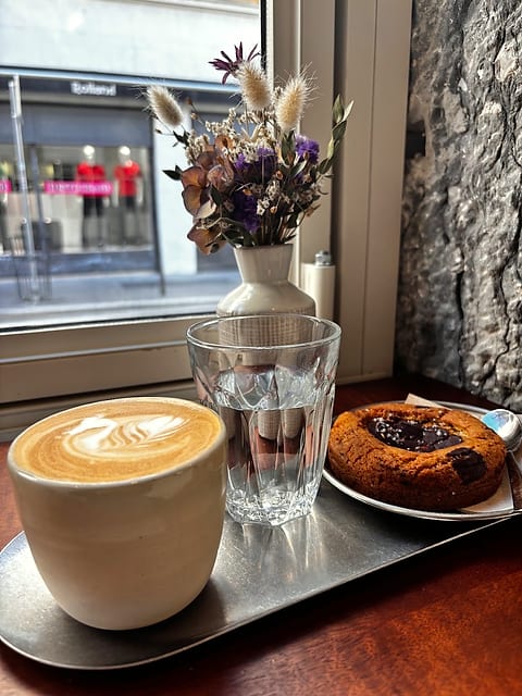 Un cappuccino au motif dessiné, servi sur un plateau en inox.
